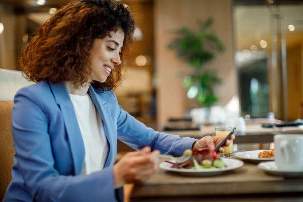istock Smiling young businesswoman using mobile phone in hotel restaurant 1773071940