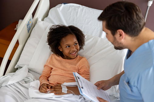 Hospitalized African American girl talking to a nurse and looking happy - healthcare and medicine concepts