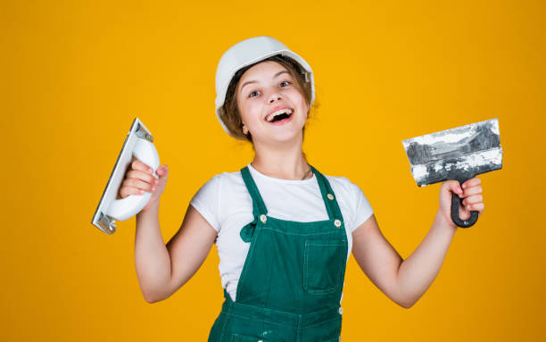 istock kid with helmet holding spatula. kid bricklayer masonry worker with helmet and trowel putty knife. house renovation. happy girl working with spatula. small builder using putty knife 1773078994