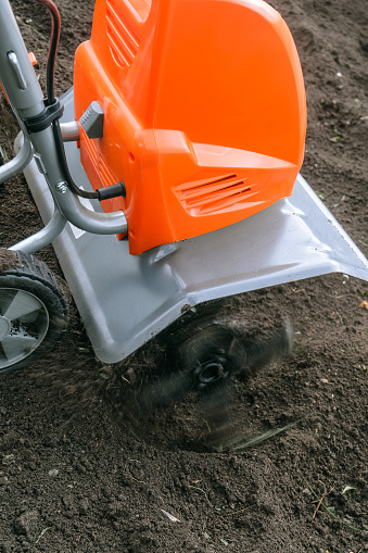 Electric cultivator cultivates soil in vegetable garden. Ripper knives spin in fast motion.