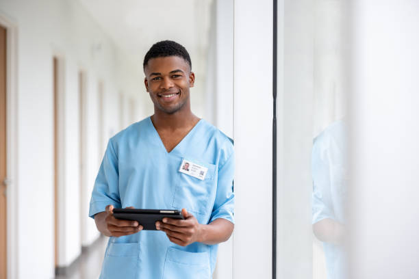 fotografii de stoc, fotografii și imagini scutite de redevențe cu asistentă medicală fericită care lucrează la un spital folosind o tabletă digitală - asistentă medicală de sex masculin