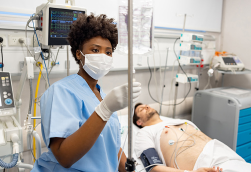 African American nurse changing an IV Drip to a patient at the hospital -  Intensive Care Unit concepts