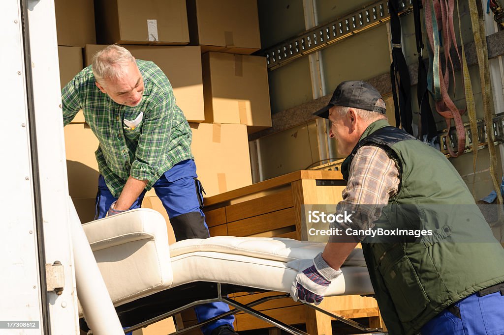 Two mover load van with furniture boxes Two male movers putting furniture and boxes  in moving truck Car Stock Photo