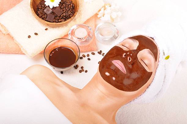 Beautiful woman with chocolate mask on her face "beautiful older woman with a chocolate mask on his face, near the coffee. candles, towels and other accessories." sponge bath sponge nature animal stock pictures, royalty-free photos & images