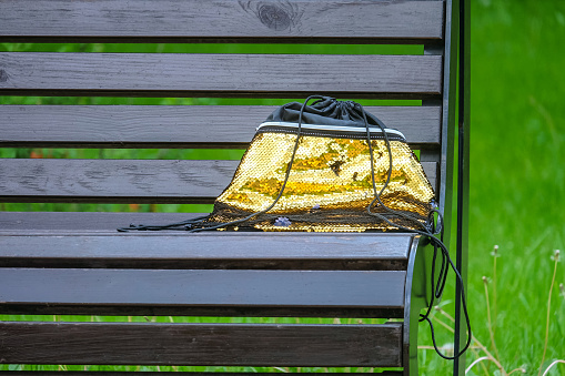 Women's handbag with golden sequins forgotten on a street bench