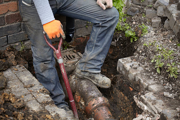 Builder Repairing Sewerage Pipe On Site Builder standing on newly exposed victorian sewerage pipe and drain prior to replacement. Shot outside at close proximity. hole in pants stock pictures, royalty-free photos & images
