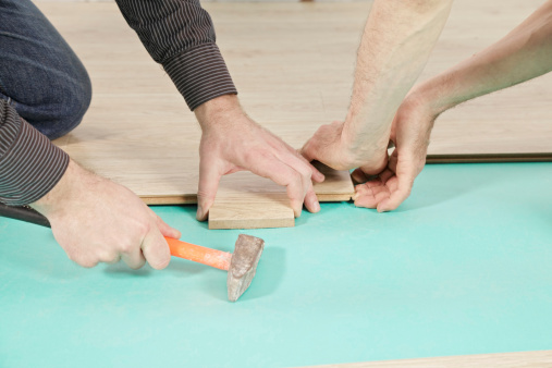 Men hands at laminate flooring process
