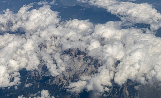 A beautiful view of white clouds enveloping the rocky tops of the mountains through the porthole window, close-up side view.