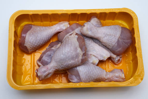 Cтоковое фото сырые куриные ножки в пластиковом контейнере на белом
