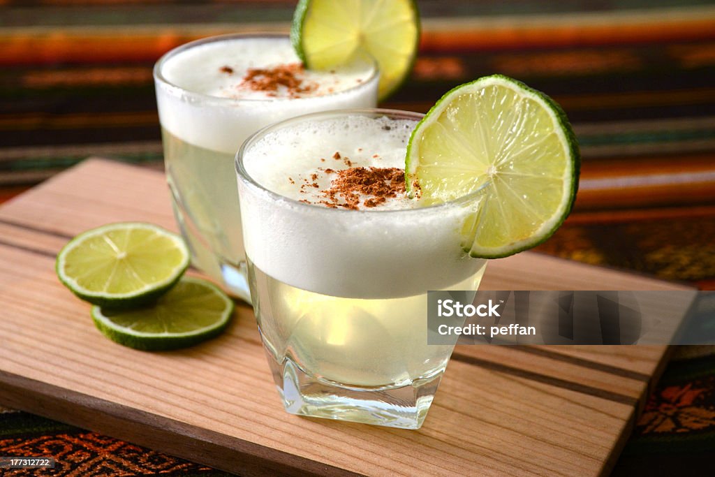 Two mini glasses of Pisco sour drinks Two Pisco Sour cocktails standing on a table with Peruvian tablecloth Pisco Sour Stock Photo