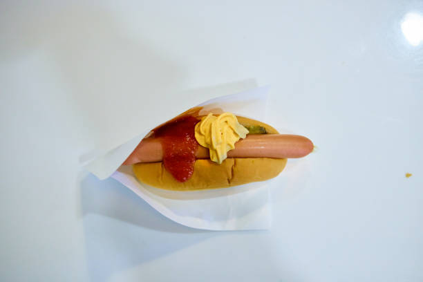 Diners savor a grilled sausage topped with mustard and served with bread.