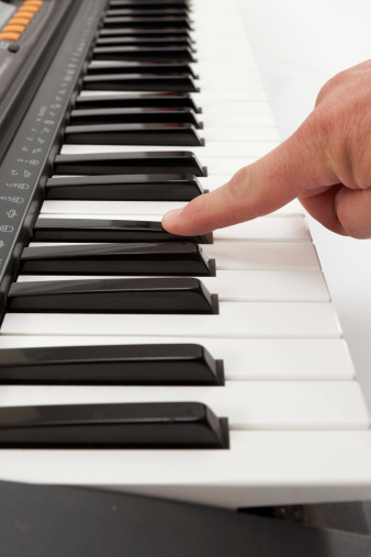Close up of 1 finger depressing piano keyboard key