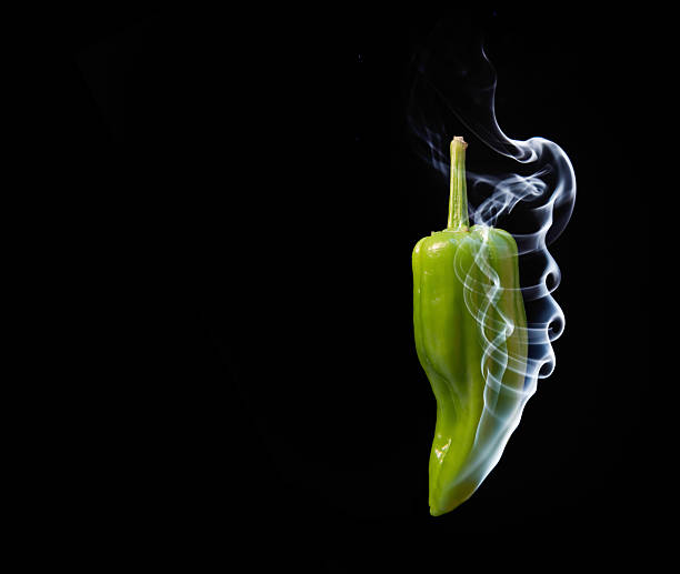 Concept of hot green chilli pepper with smoke coming out of tip