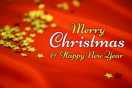 Red satin background with lots of little golden stars on it. Merry Christmas and Happy New Year lettering.