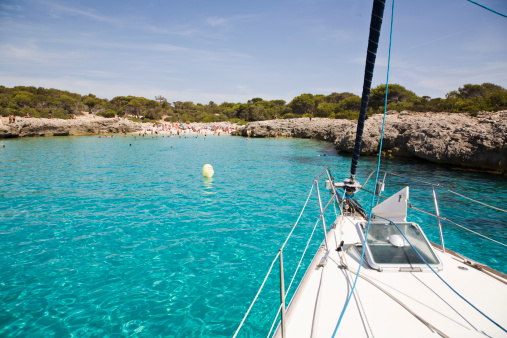 Sailboat dropping anchor in a cove in Menorca