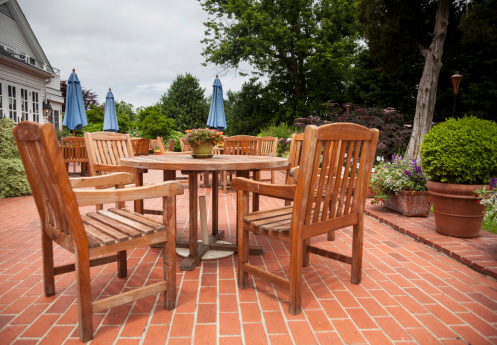 Many wooden teak tables and chairs on brick pation in cafe or restaurant