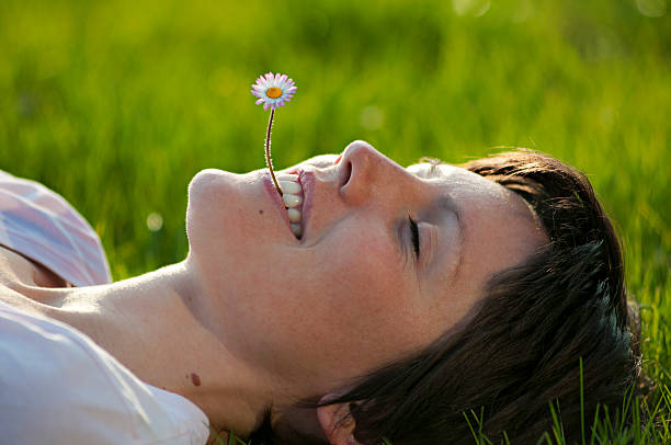 Girl lying on grass with her hair full of marguerites spread around her head