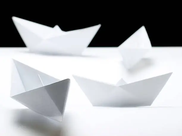 Several origami paperships on a white background.