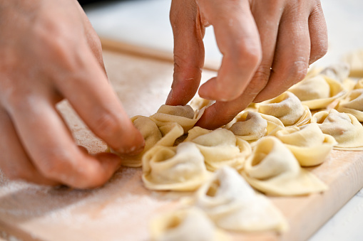 Female hands filling dough with minced meat to prepare Turkish dumpling called manti