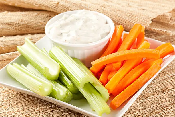 Photo of Container of ranch dressing with celery and carrot sticks