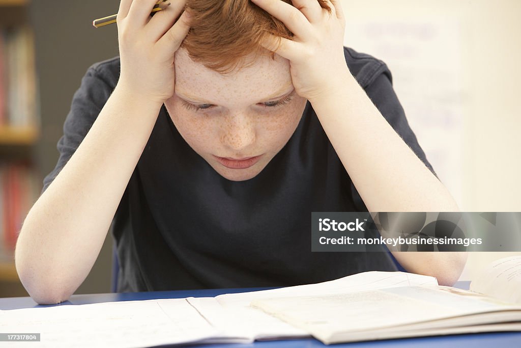 Sottolineato Scolaro studiando In aula - Foto stock royalty-free di Fare fatica