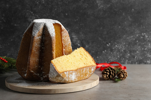 Delicious Pandoro cake with powdered sugar and Christmas decor on grey table. Space for text