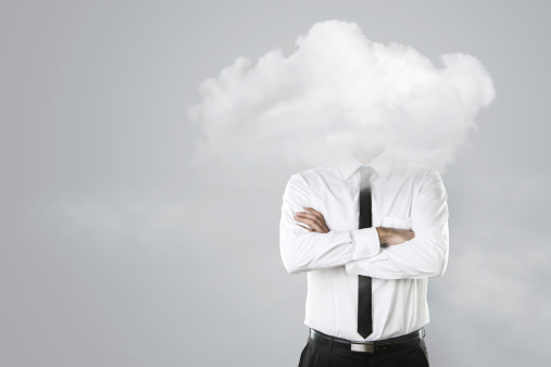 Young businessman with head in the clouds over gray background with copy space
