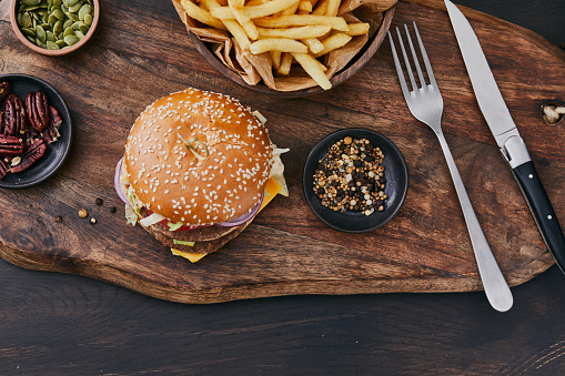 Fresh, tasty and delicious double beef cheeseburger with French fries, tomato, Spanish onion, served  on a plate, bar, restaurant or home kitchen table, close up view with copy space, representing fast food and city life, indulgence and joy through gourmet lifestyle