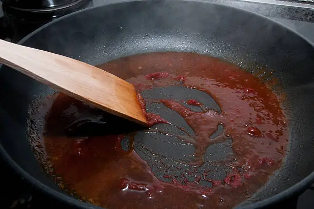 In a pan is making a sauce with tomato paste and white wine