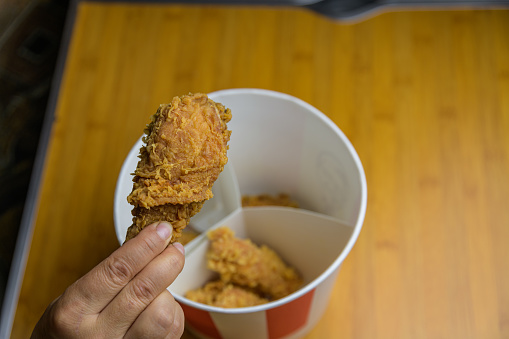 Hand holding crispy fried chicken. Fast food