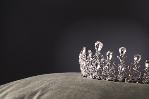 Beautiful silver tiara with diamonds on grey cloth. Space for text