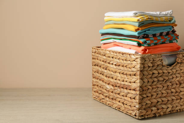 istock Wicker laundry basket with clean clothes on floor near beige wall. Space for text 1773200146