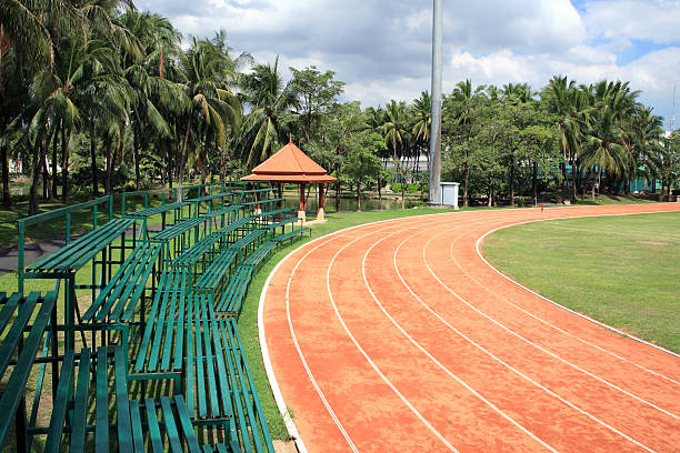 Athletic curved running track with green bleachers and Palm environment
