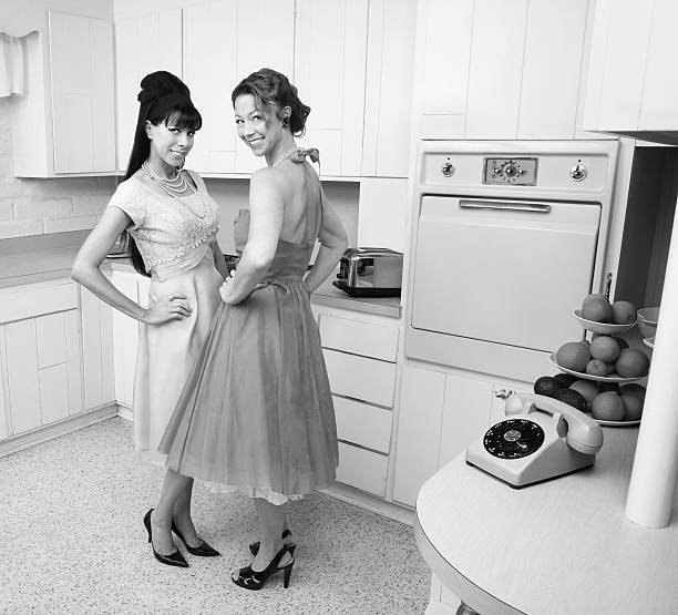 Happy Women Happy Caucasian housewives in a retro kitchen with hand on hips retro 1950s kitchen stock pictures, royalty-free photos & images