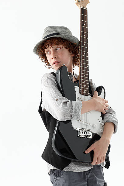 Cool young boy holding an electric guitar Eight year old boy with hat and red hair holds an electric guitar rockabilly boys stock pictures, royalty-free photos & images
