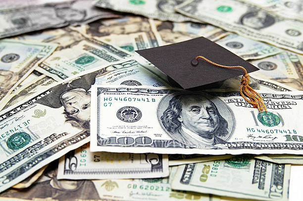education costs mini graduation cap on US money -- education costs debt photos stock pictures, royalty-free photos & images
