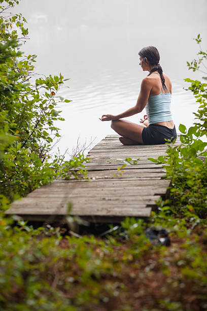 istock Woman meditating on dock by lake 177325375