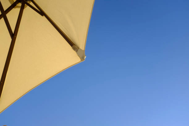 Yellow parasol umbrella on a blue sunny summer sky background
