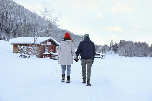 Couple walking in mountains on snowy day, back view. Winter vacation