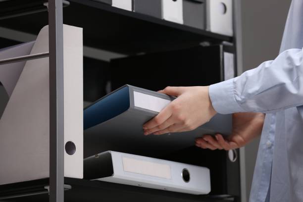 istock Woman taking folder with documents from shelf in office, closeup 1773273378