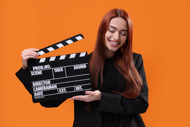 istock Happy actress with clapperboard on orange background. Film industry 1773274503