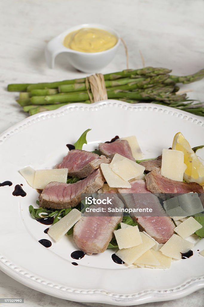 Manzo con insalata di rucola, parmigiano - Foto stock royalty-free di Aceto balsamico