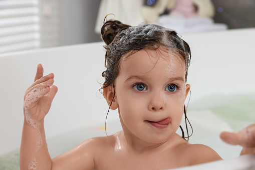 Children having fun splashing and playing in a bubble bath in the bathroom