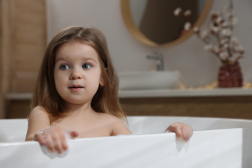 Cute little girl in bathtub at home. Hair washing