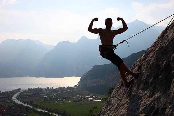 silhouette d'un grimpeur contracter biceps rock - mountain rock sun european alps photos et images de collection