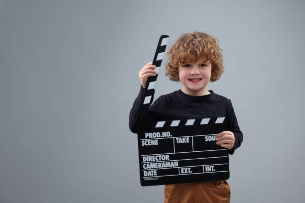 istock Smiling cute boy with clapperboard on grey background, space for text. Little actor 1773287714
