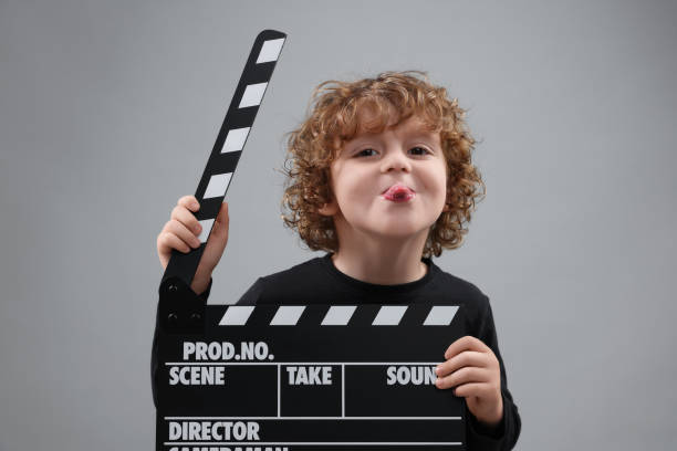 istock Happy cute boy with clapperboard on grey background. Little actor 1773287728