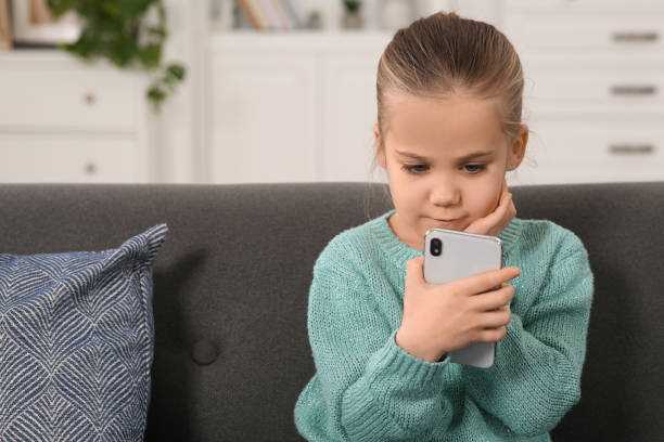 istock Little girl using smartphone on sofa at home. Internet addiction 1773288824