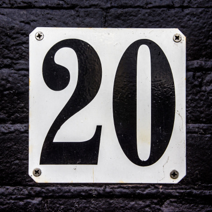 modern house number twenty attached to al black painted brick wall