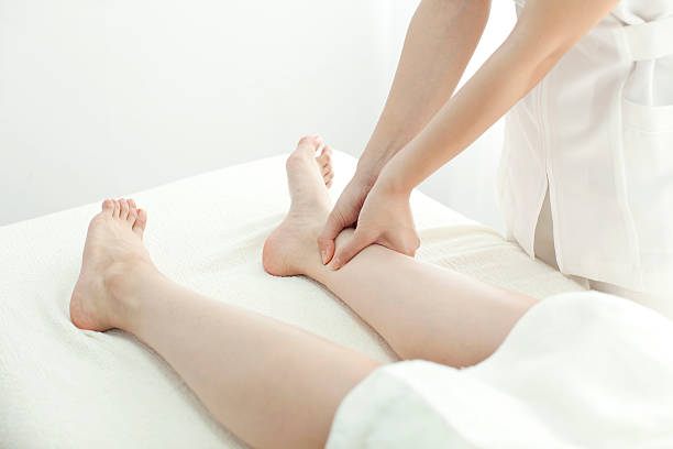 el esteticista que masajes una pierna - massaging human arm obscured face only women fotografías e imágenes de stock